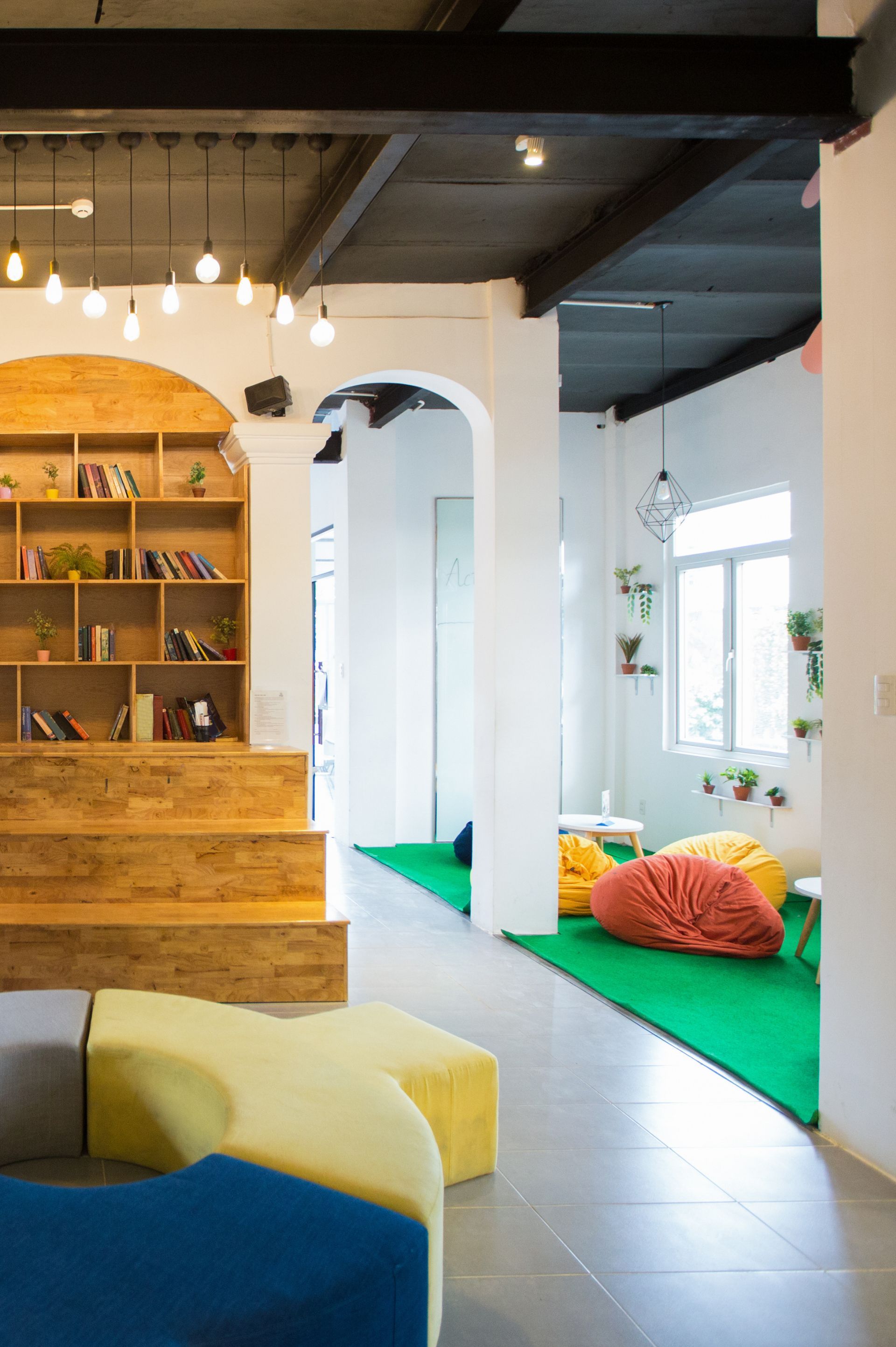 Modern interior with reading nook, green carpet, beanbags, and bookshelves.