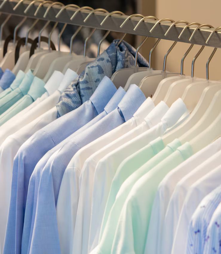 Shirts on hangers in a color gradient of blues, whites, and greens.