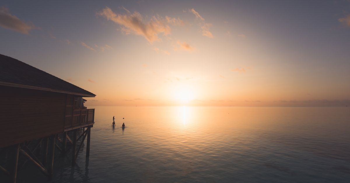 Maldives honeymoon couple on an overwater villa deck at sunset