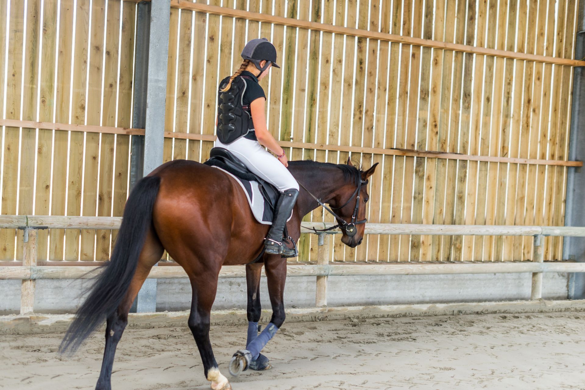 A woman is riding a brown horse in an arena.