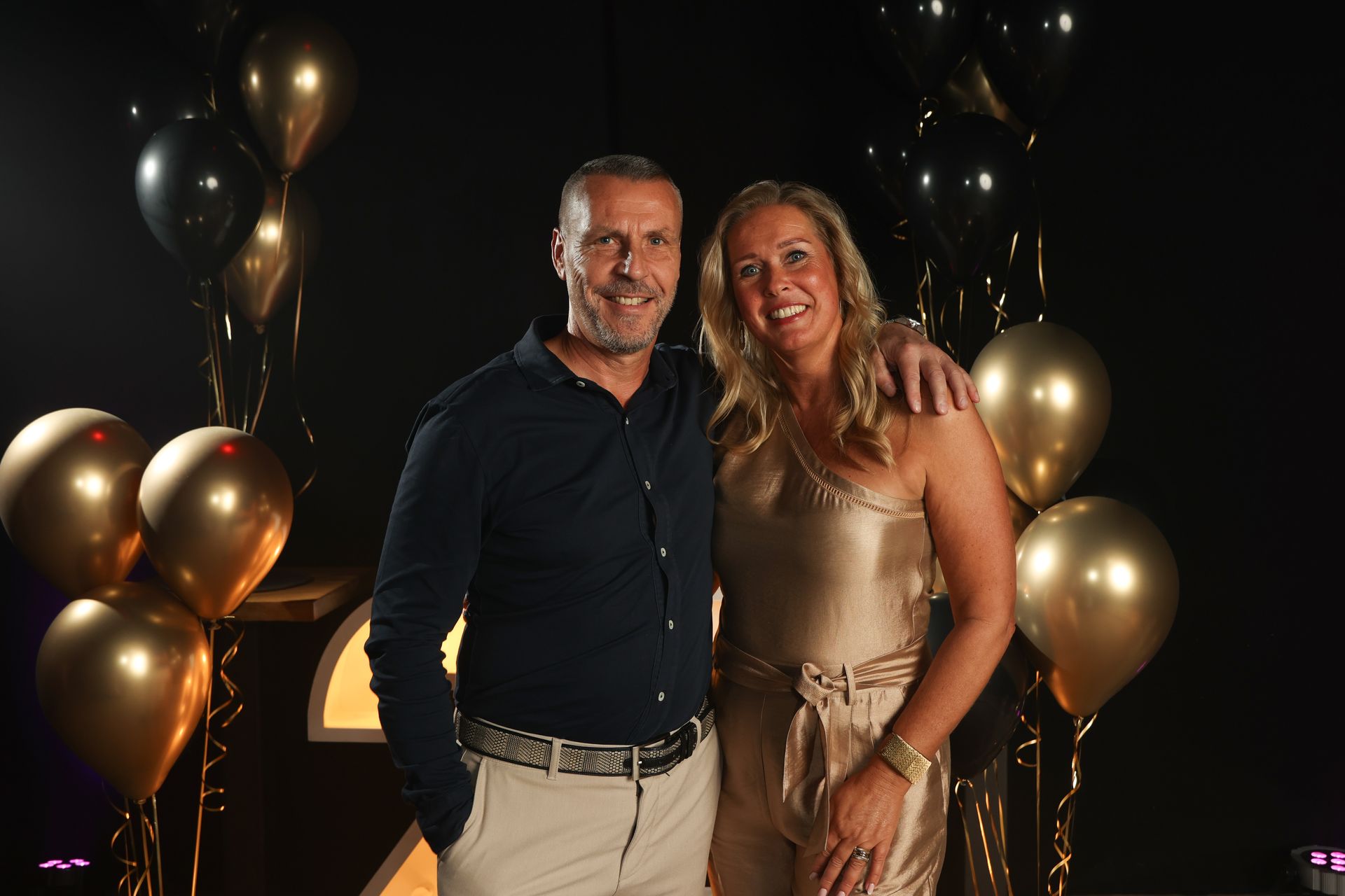 Een man en een vrouw staan ​​met hun armen om elkaar heen voor ballonnen.