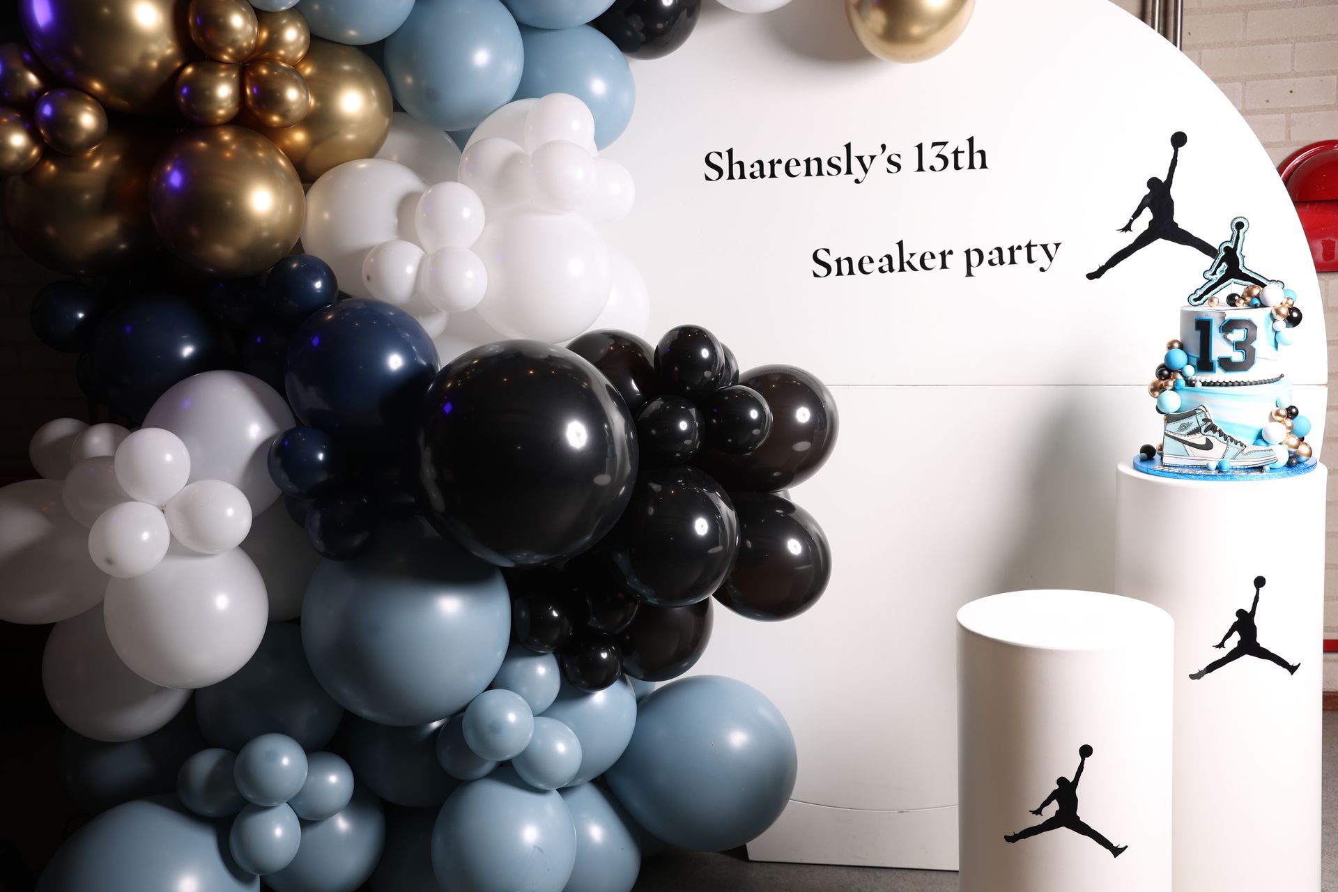 Een ballonnenboog, een witte achtergrond, een taart en Jordan-logo's voor een 