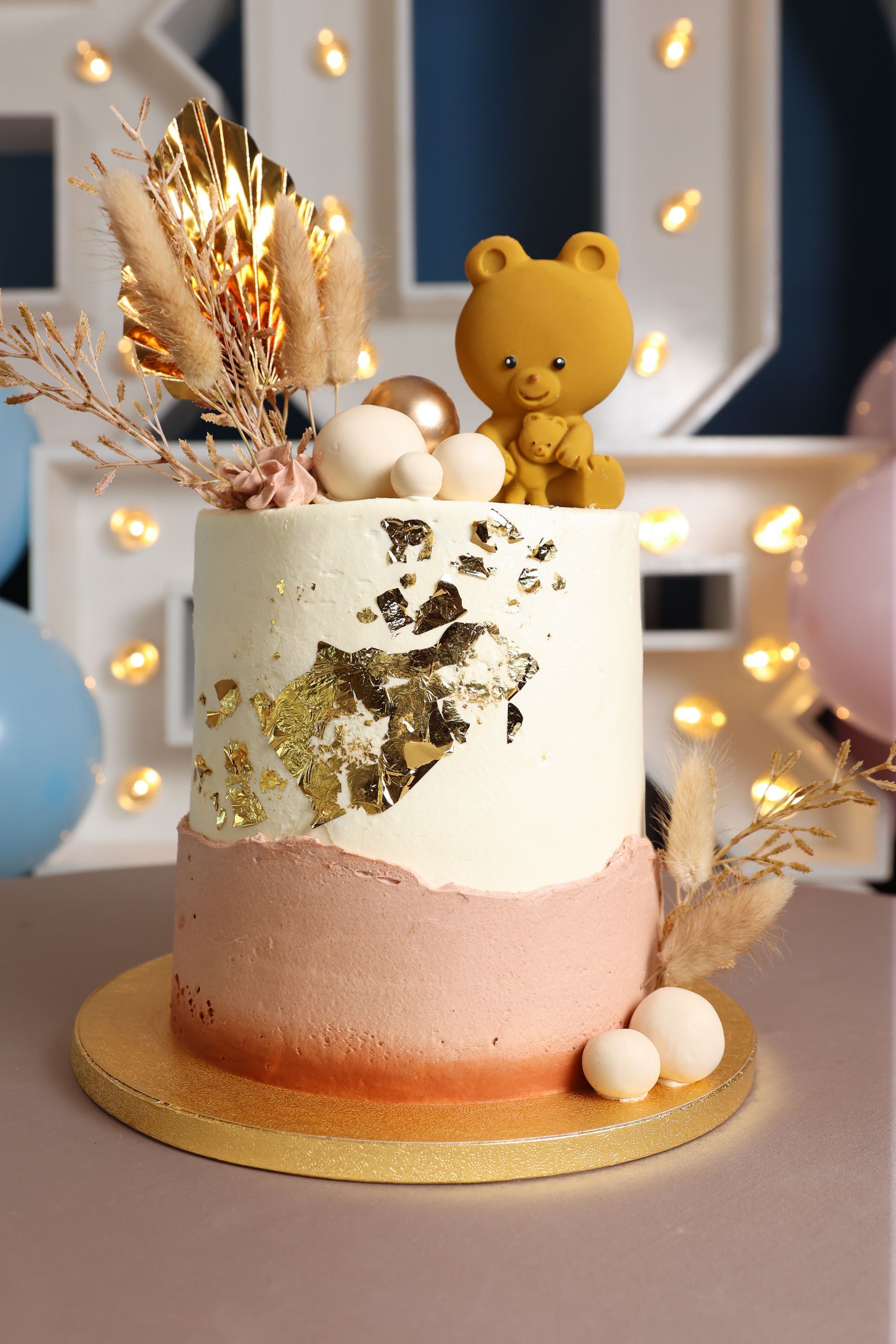 Taart met bladgoud, een teddybeer als decoratie en pampasgras.