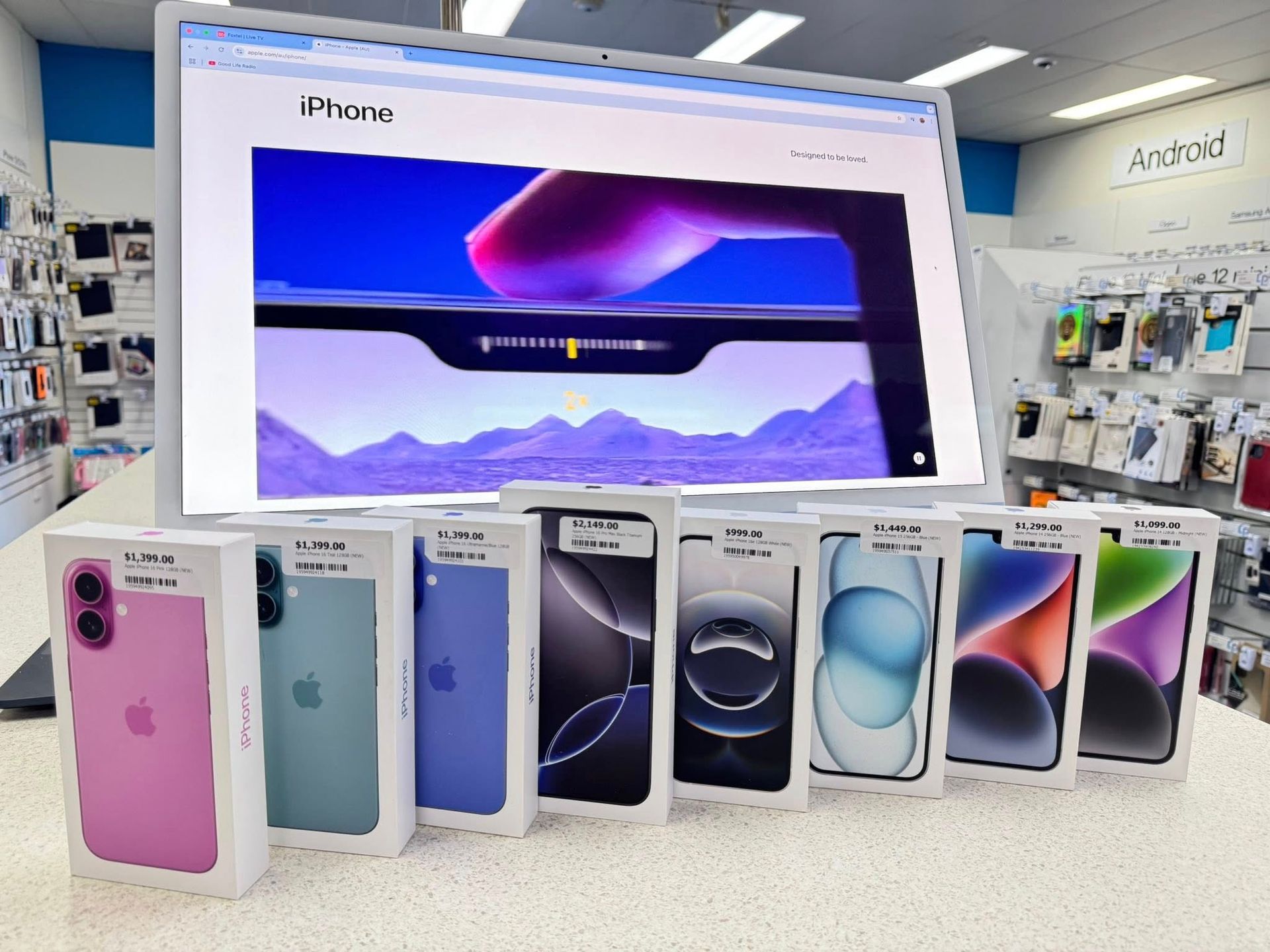 Row of iPhone Boxes in Various Colours in Front of a Computer Screen Displaying — Phone Hut in Alice Springs, NT