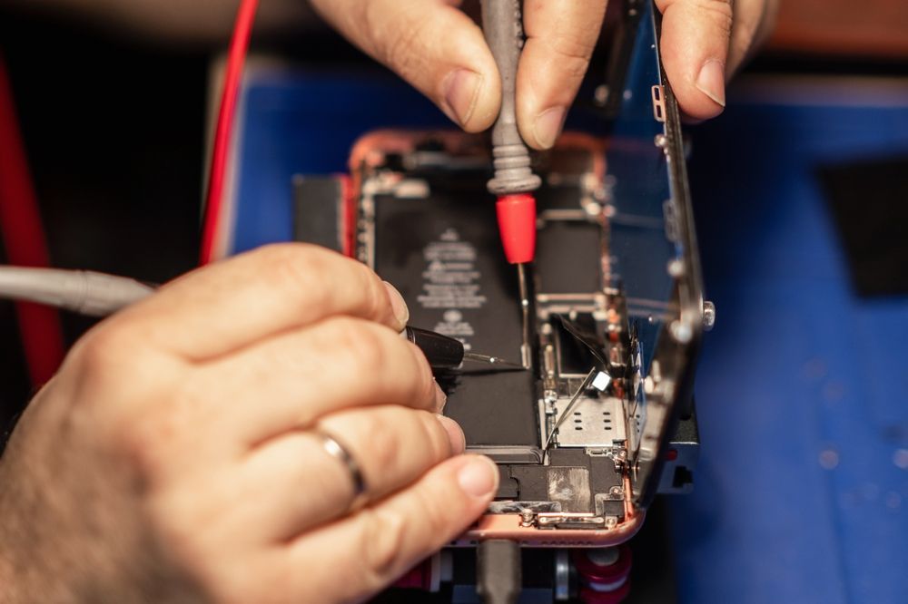 Technician Testing Smartphone Circuit Board With Multimeter Probes