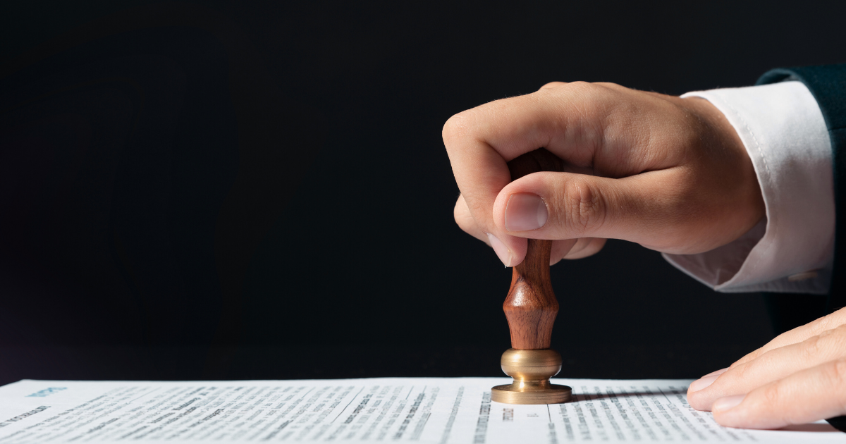 Hand stamping a document with a wooden seal on a desk