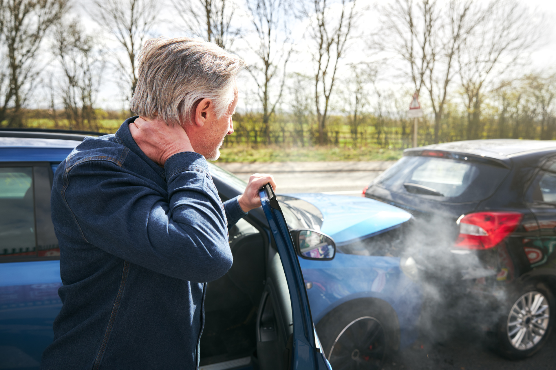 Person beside open car door with visible exhaust smoke between two parked cars