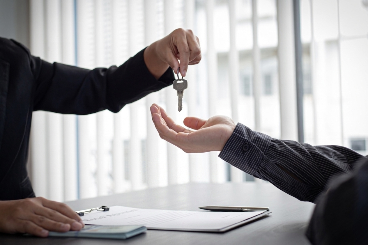 Handing over house keys across a desk in a bright office