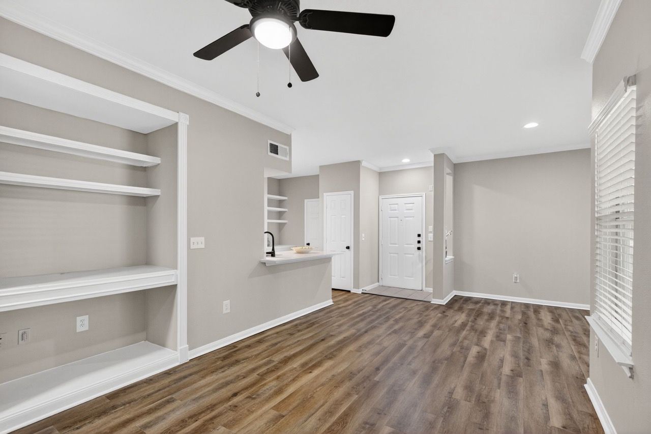Bright living area with built-in shelves, a kitchen island, and a ceiling fan.