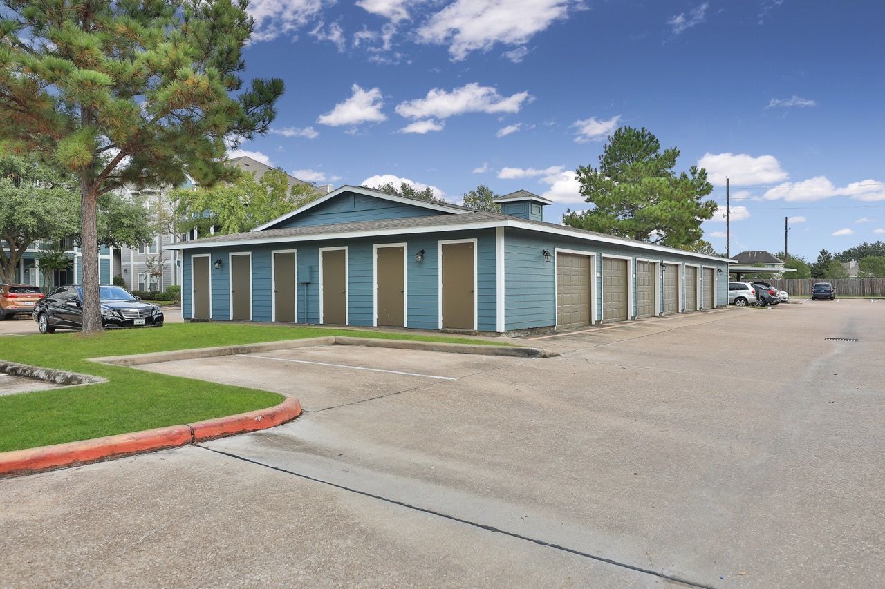 Blue, one-story building with a line of beige garage doors along a paved parking lot.