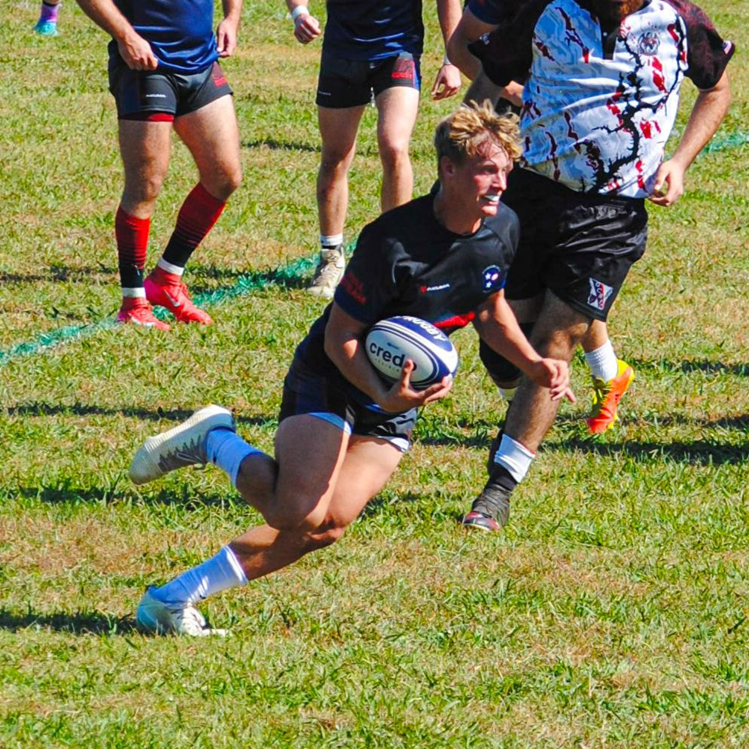 A group of people are playing rugby on a field.