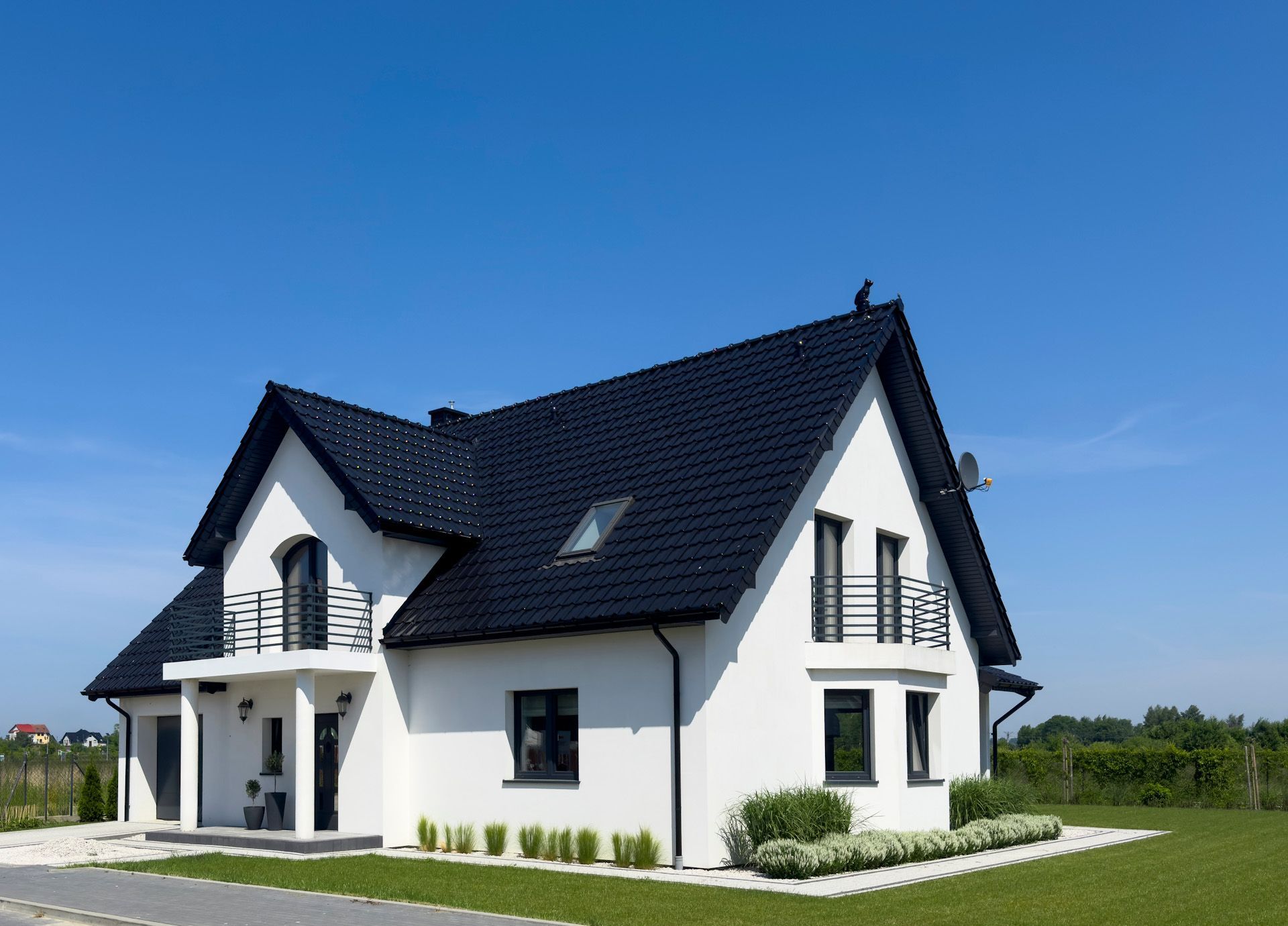 A white house with a black roof and a balcony