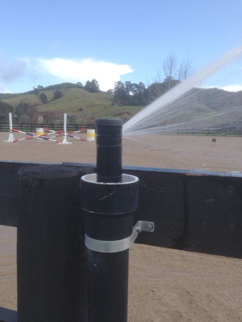 A fence with a sprinkler spraying water on it