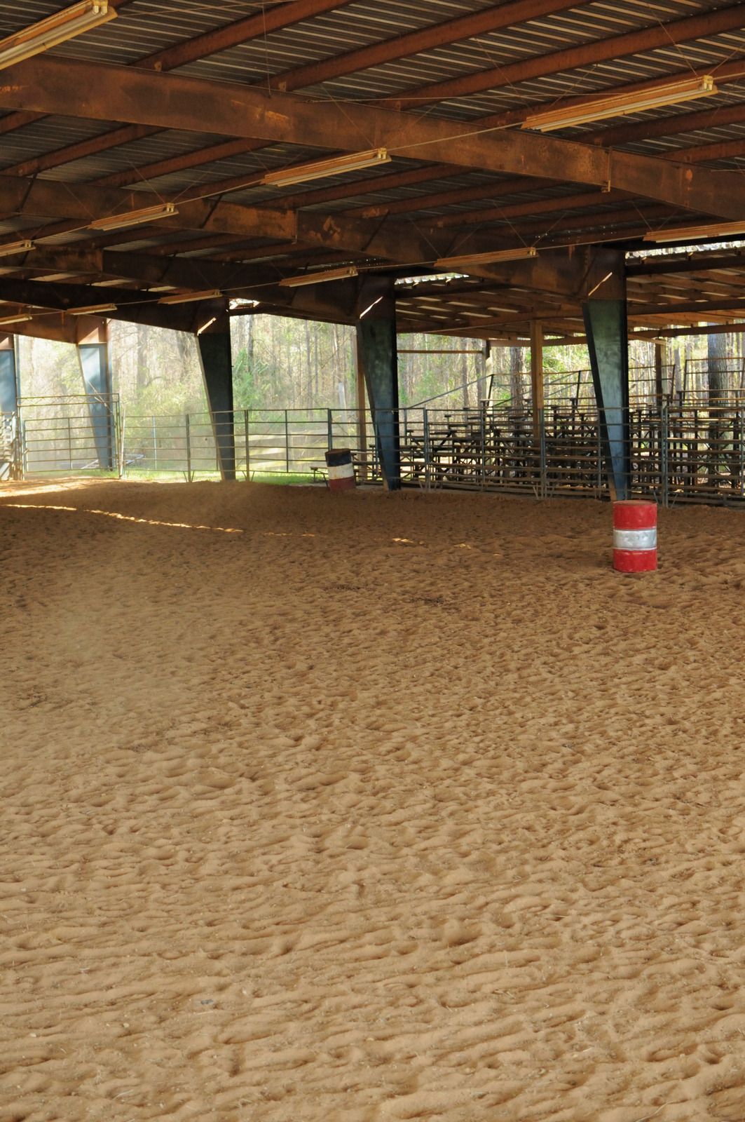 There is a red and white barrel in the middle of a dirt arena.