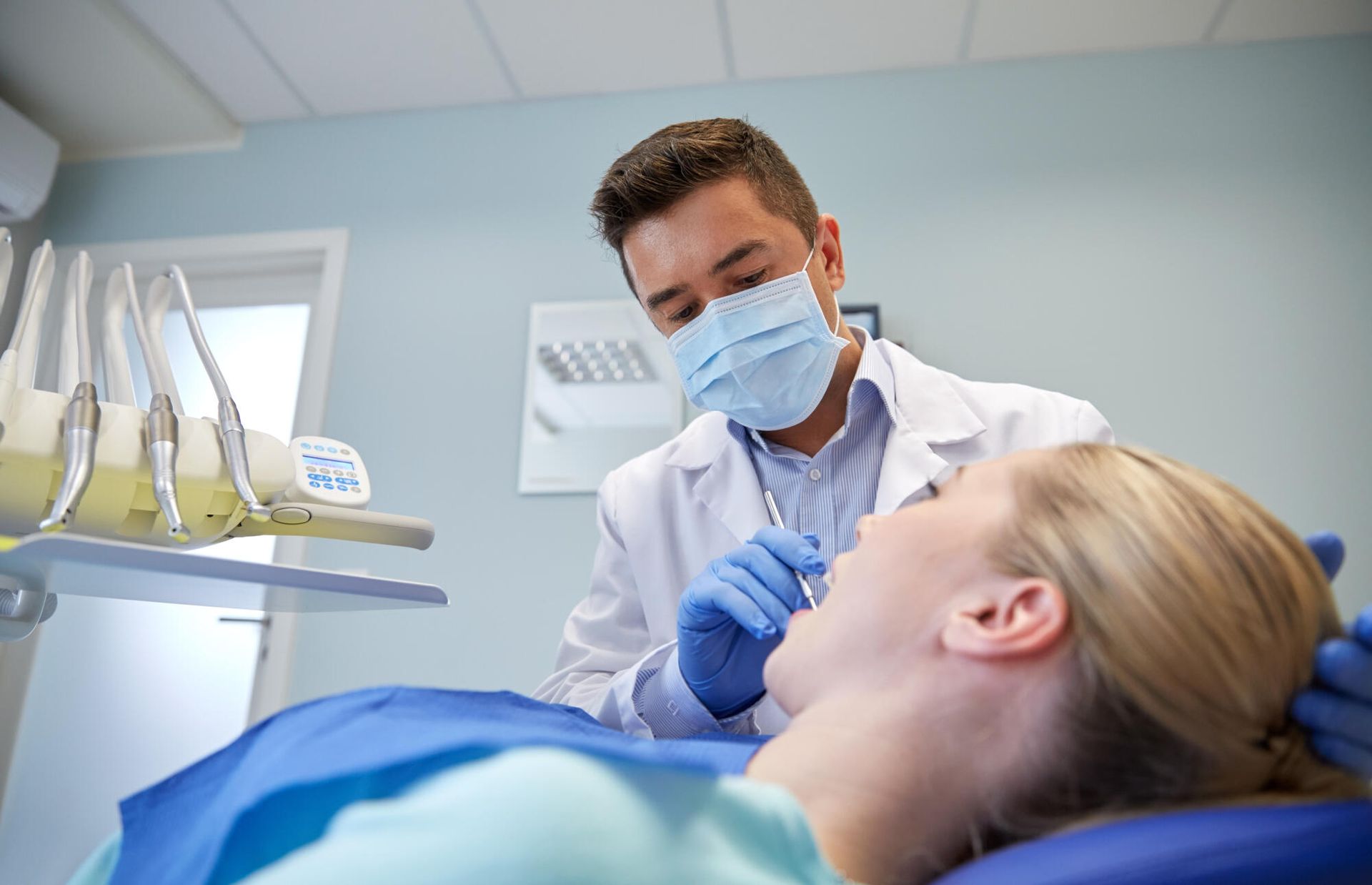 Dentist examining a patient in a bright dental office, wearing a mask and gloves