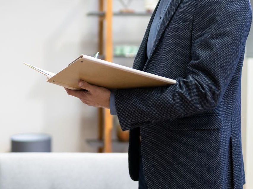 A man in a suit is holding a clipboard in his hand.