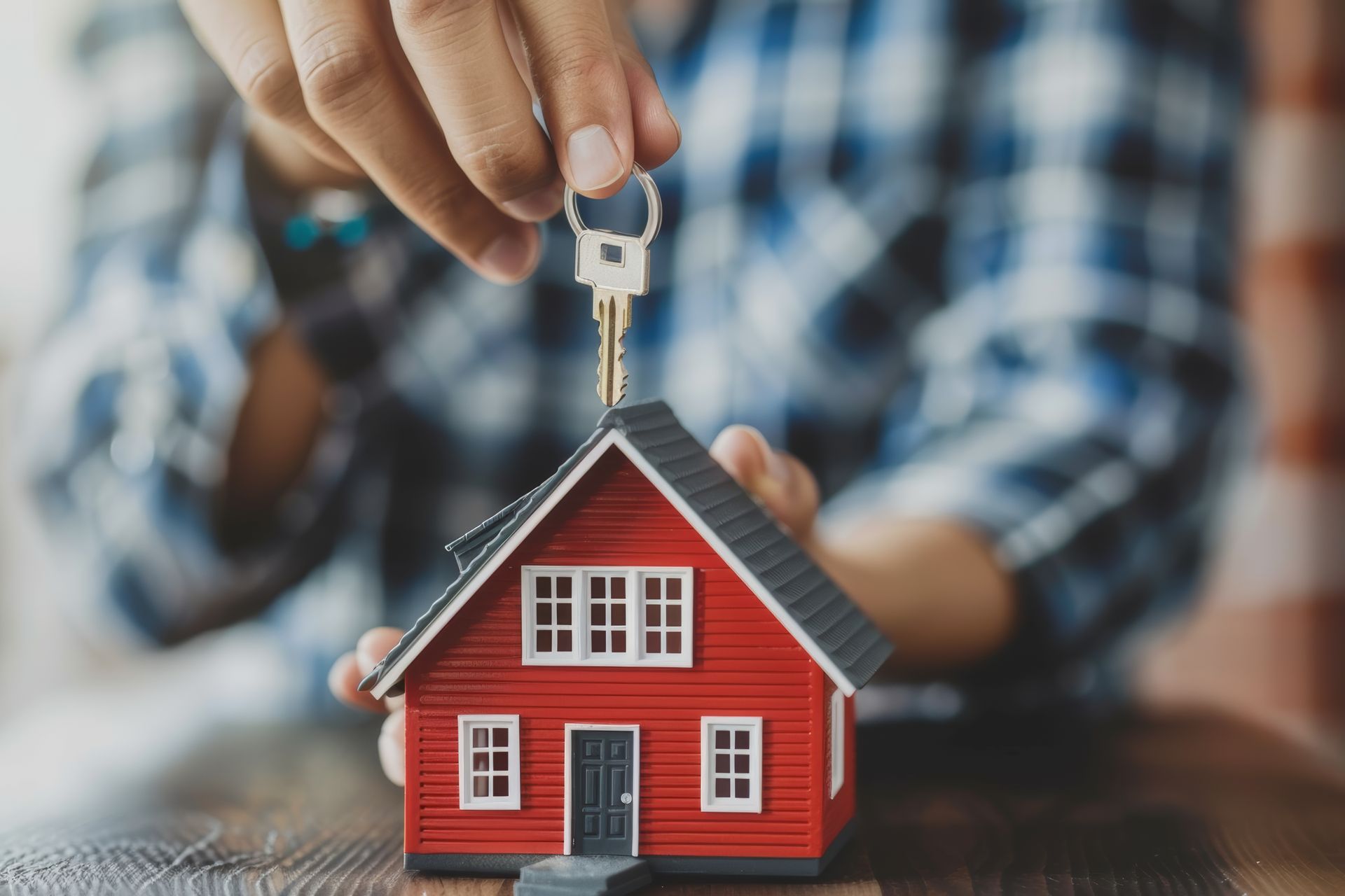 A person is putting a key on top of a model house.