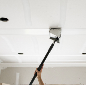 A person using a Drywall box to Skim coat a ceiling.