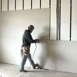 A man installing Sheetrock.