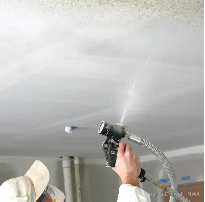 Spraying orange peel drywall texture onto a ceiling with a hopper gun