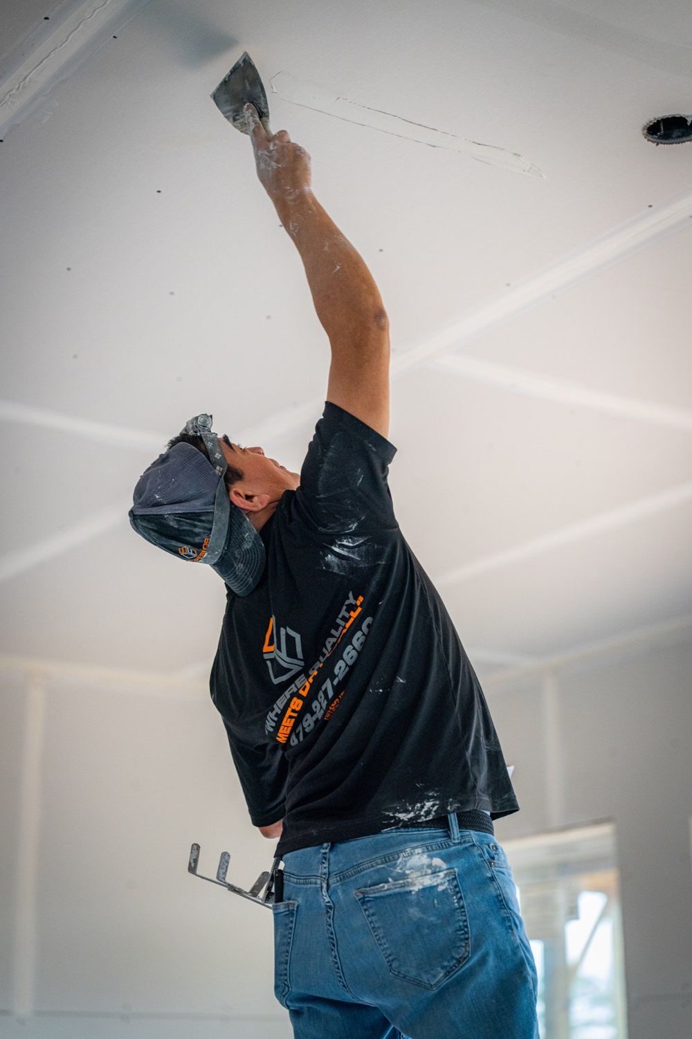Superior Drywall & Finishing crew member taping ceiling drywall seams, the hang-and-finish work we do in NWA garages