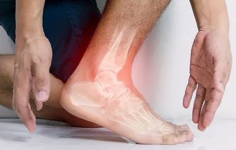 Person holding a painful ankle with a red glow indicating injury or inflammation