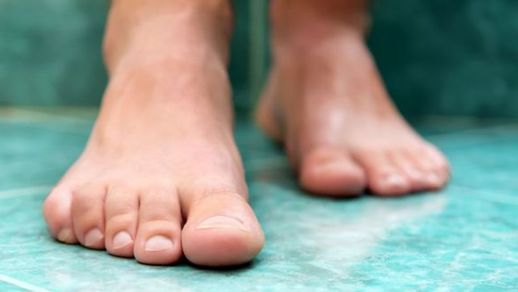 Close-up of bare feet standing on a turquoise floor