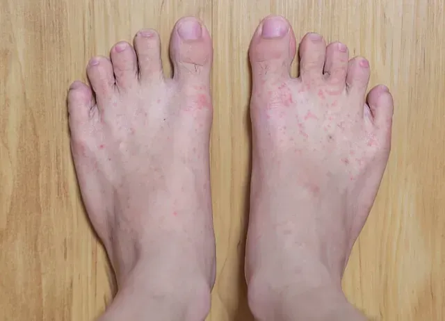 Pair of bare feet on a wooden floor, viewed from above.