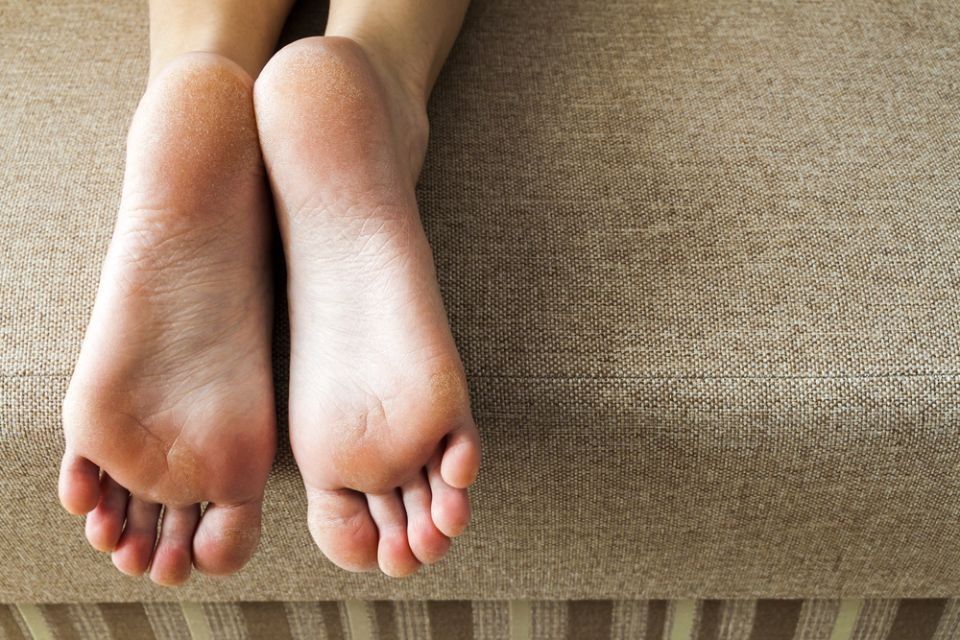 Bare feet resting on a beige couch, soles facing the camera.