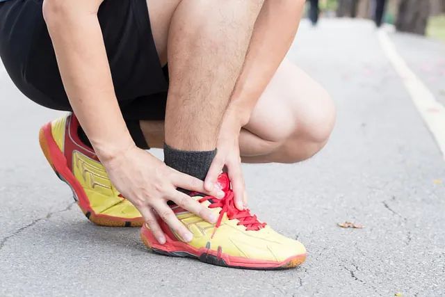 Runner crouching and holding a bright yellow-and-red sneaker on a road