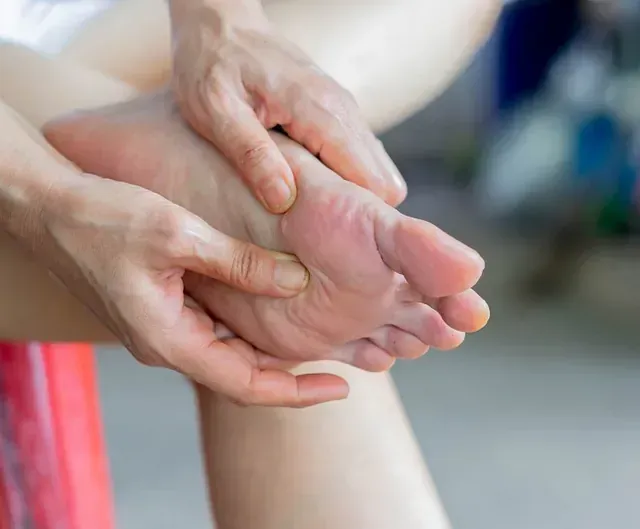 Hands gently holding and examining a bare foot, close-up on skin and toes.