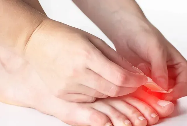Hands pressing a painful red toe, indicating foot pain or injury