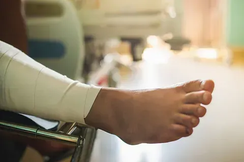Bare foot resting on a wheelchair footrest in a bright hospital room