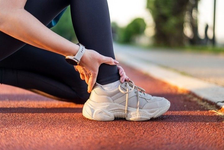 Runner tying shoelace on track at sunrise