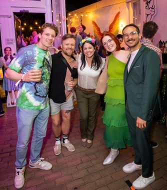 Friends in colorful costumes smiling together at an evening event
