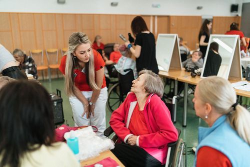 People chatting at a community event with tables, monitors, and papers in a bright room
