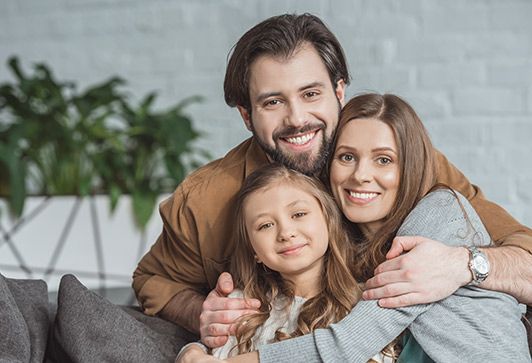 Smiling family hugging on a couch in a bright living room