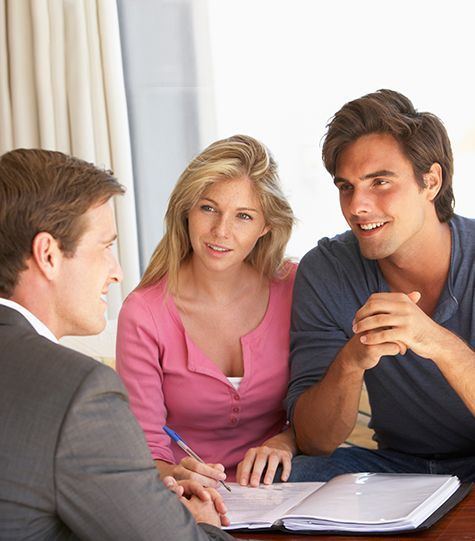 Three people in a meeting, discussing paperwork at a table