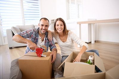 Smiling couple sits on the floor among moving boxes in a bright room
