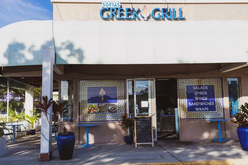 The front of a greek grill restaurant with a white awning