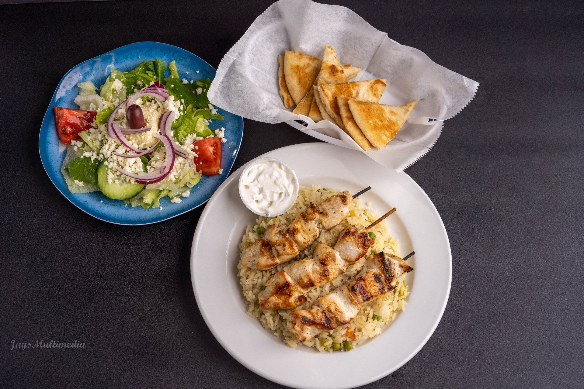 A plate of food with a salad and pita bread on a table.