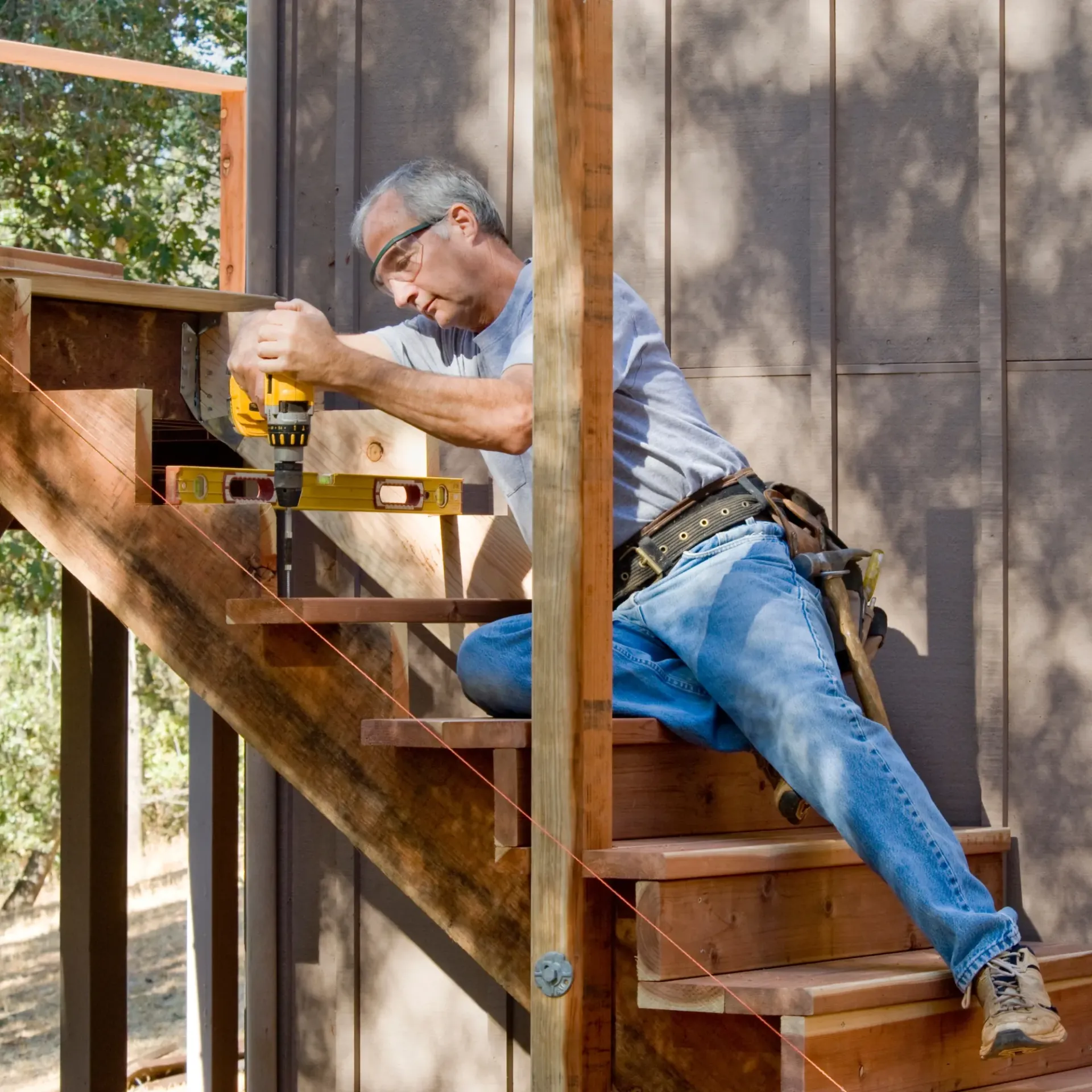 Sanchez Electric and Remodeling - A man is working on a wooden staircase with a drill
