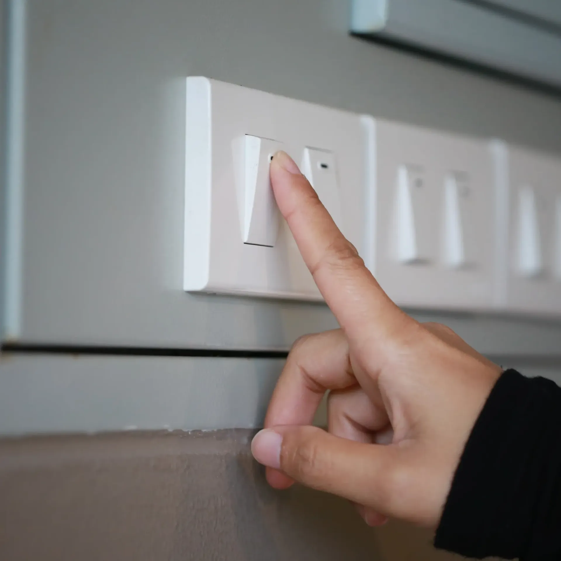 Sanchez Electric and Remodeling - A person is pressing a light switch with their finger