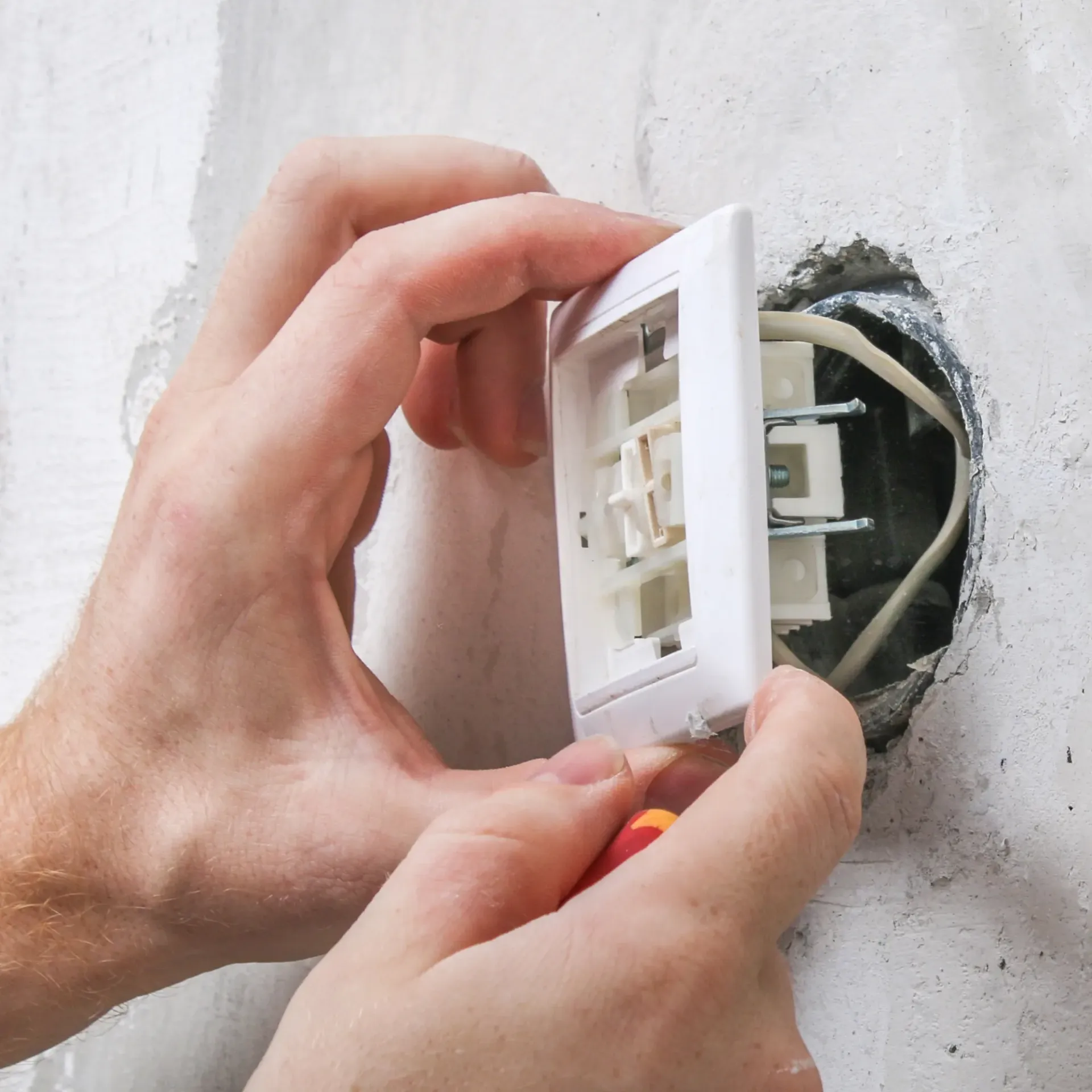 Sanchez Electric and Remodeling - A person is installing a light switch on a wall.
