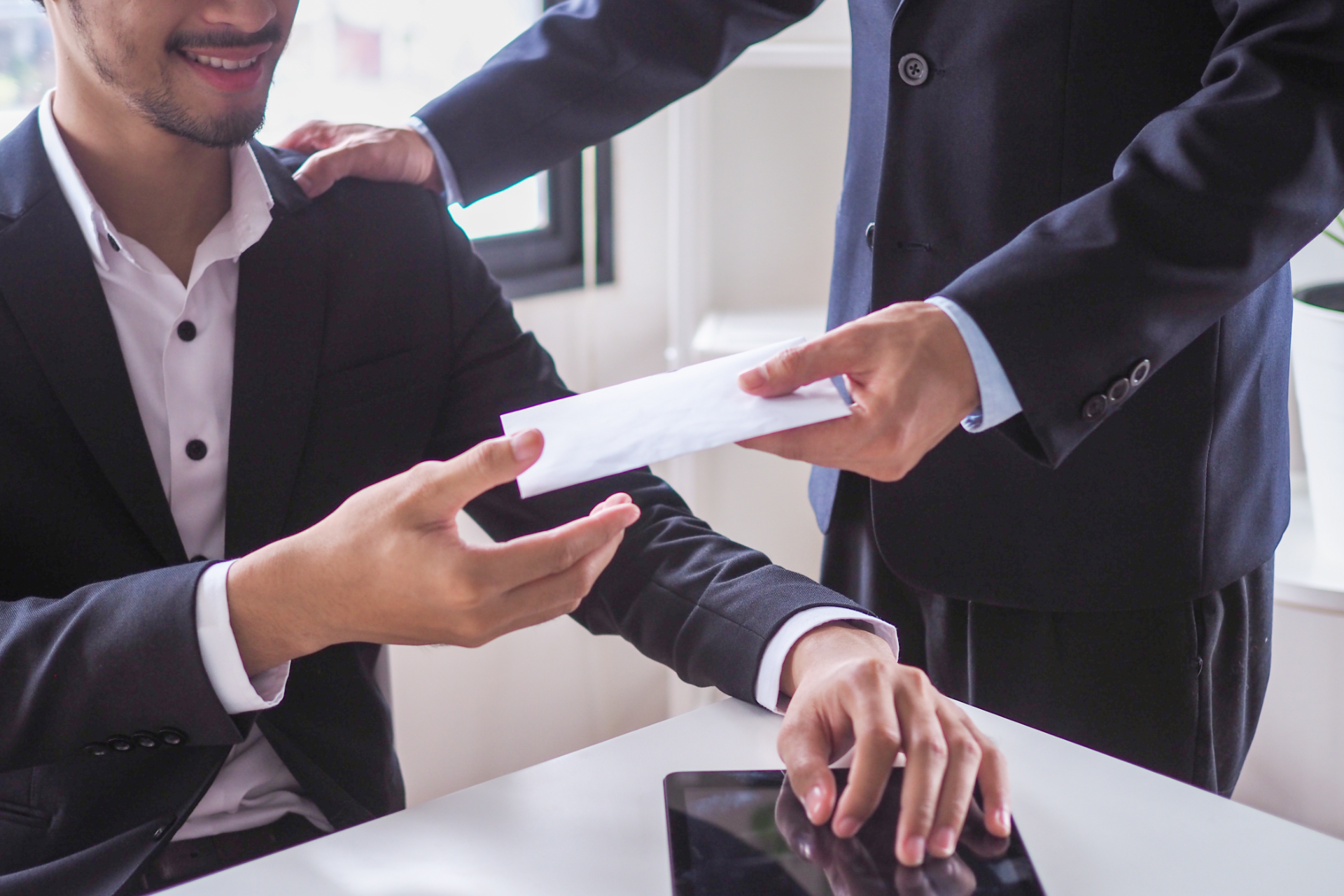 Two businesspeople exchanging a document in a bright office conference room