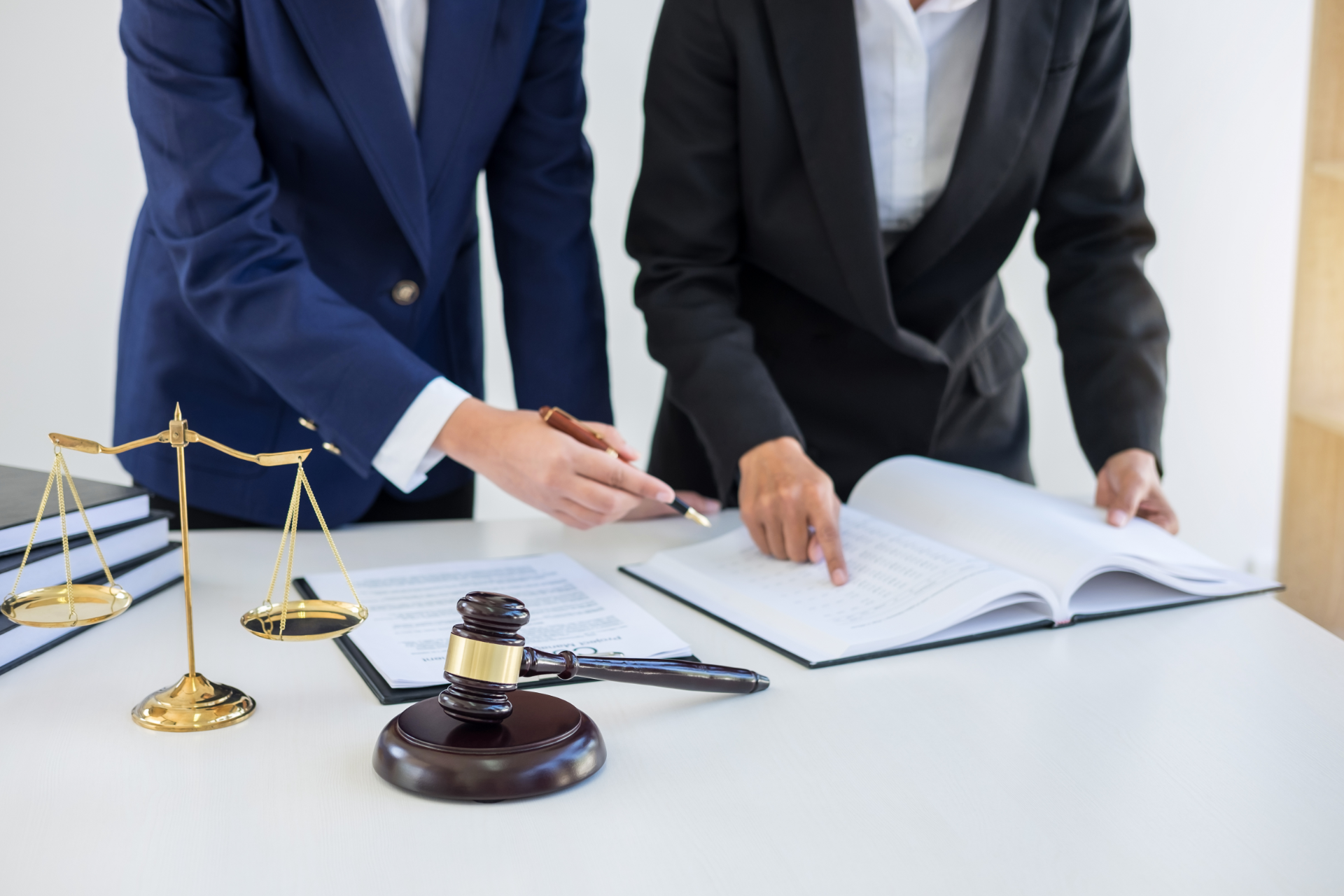 Two lawyers in suits reviewing documents beside a gavel and scales of justice