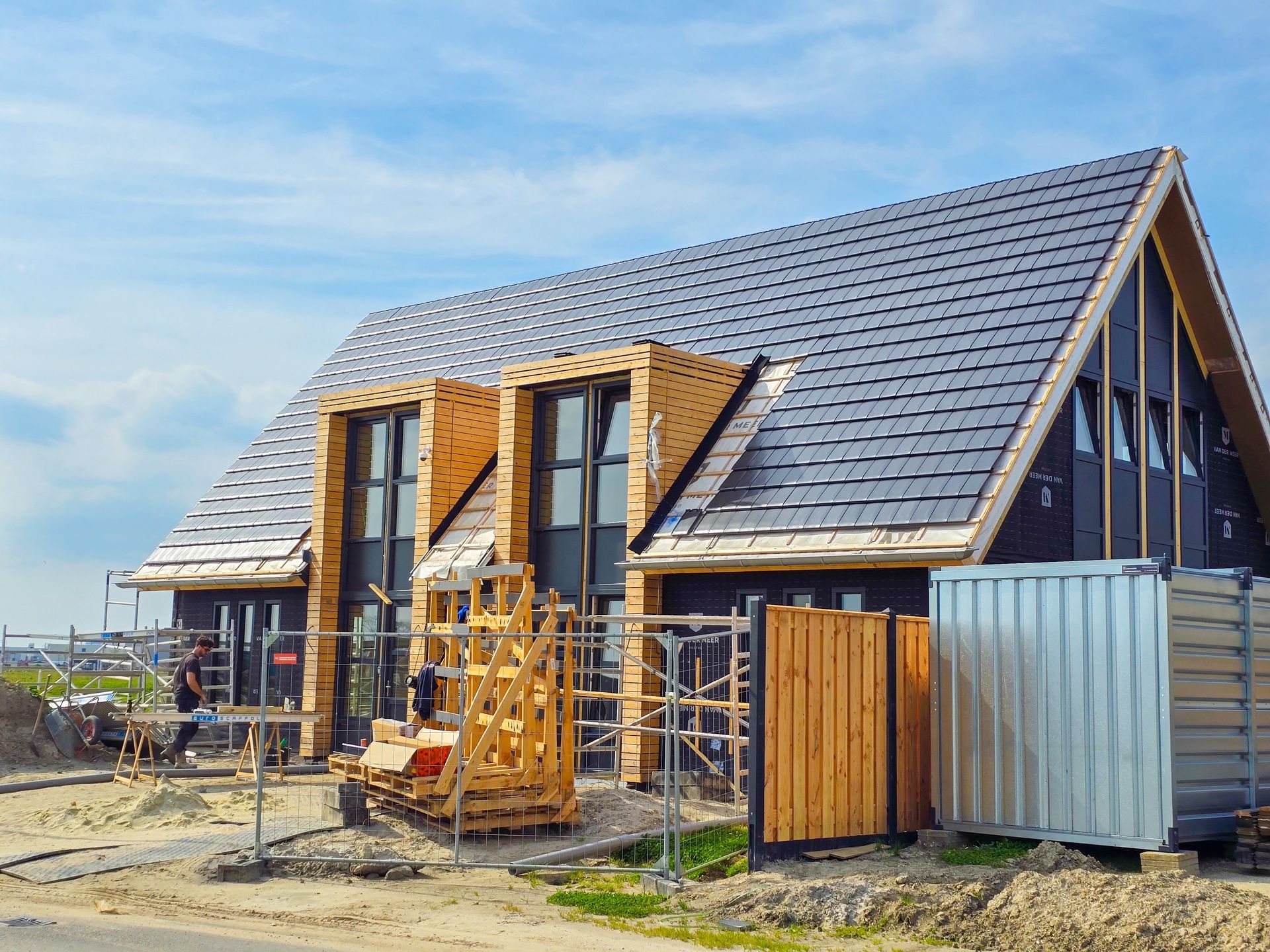 Construction of a modern, black-sided house with a dark roof