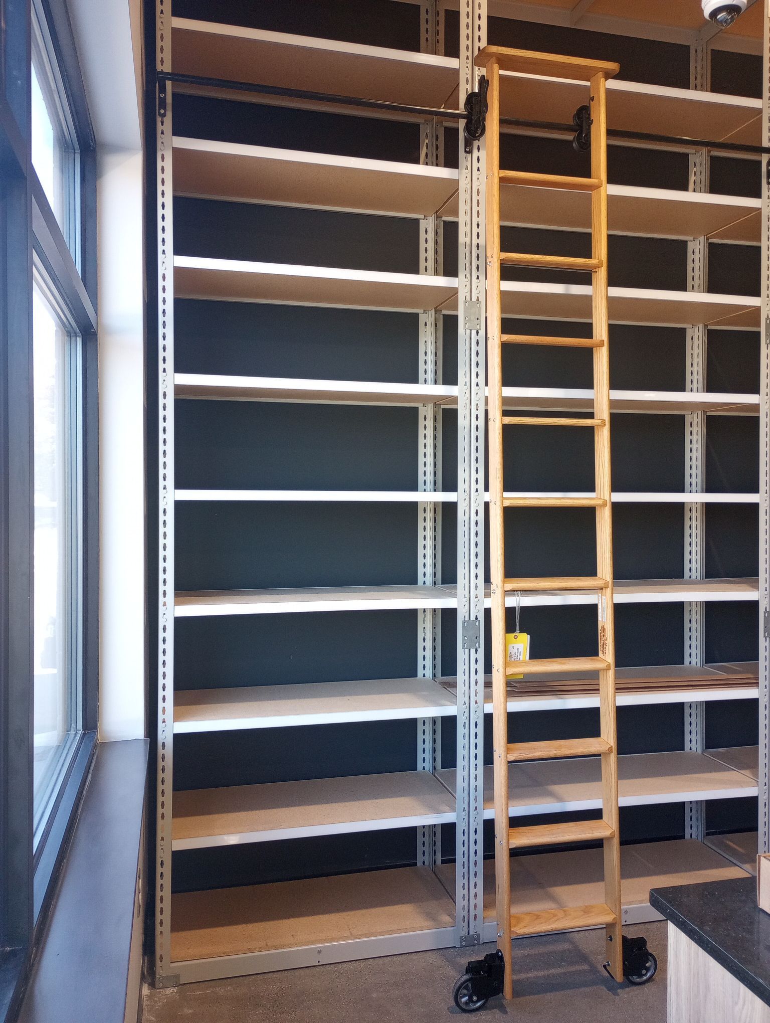 A wooden ladder is attached to a wall of shelves