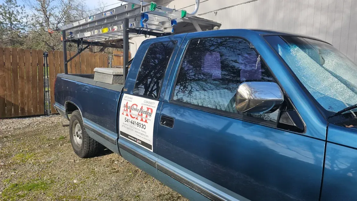 Blue pickup truck parked outside, with a rack and business signage on the door.