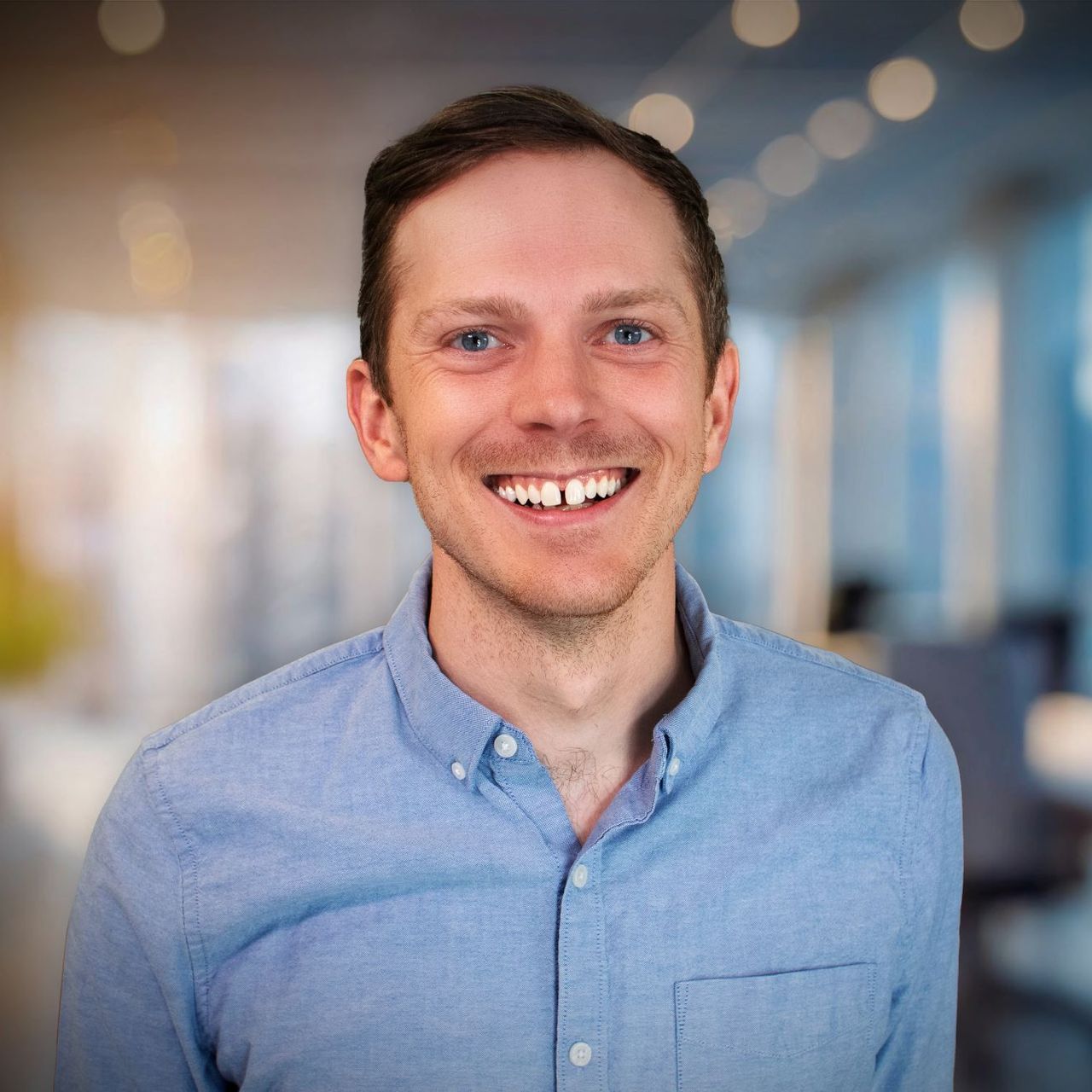 A man in a blue shirt is smiling for the camera.